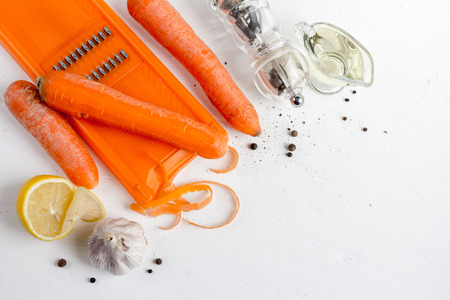 The ingredients to cook Korean carrots: carrots, butter, hot pepper, coriander, lemon on a white table.の写真素材