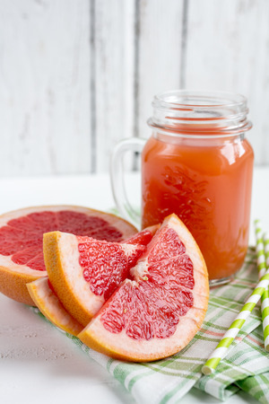 Grapefruit juice in a jar, grapefruit on a white wooden background. Selective focus.の写真素材