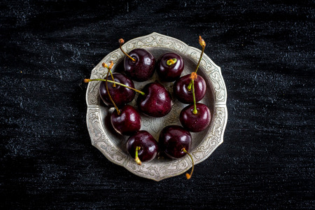 Cherry in a metal bowl on a black background. Selective focus.の写真素材