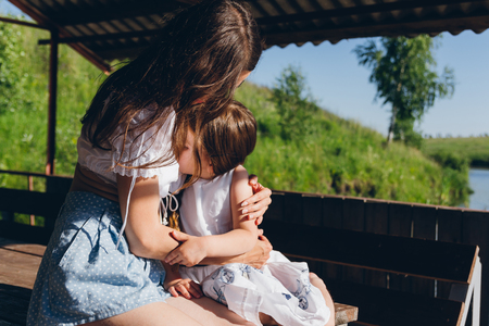 Daughter hugging mother in the gazebo on a hot summer day. The concept of relaxation and happiness. Toning.の写真素材
