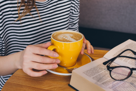 Cup of coffee with a beautiful pattern in the girl's hands. Selective focus. Toning.の写真素材