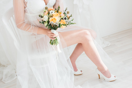 Boudoir bride's morning. Young beautiful woman with a bouquet in a negligee preparing for their wedding day. Toning.の写真素材