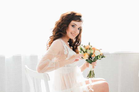 Boudoir bride's morning. Young beautiful woman with a bouquet in a negligee preparing for their wedding day. Toning.の写真素材