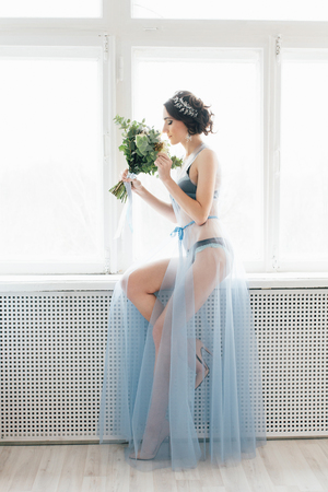 Boudoir bride's morning. Young beautiful woman with a bouquet in a negligee preparing for their wedding day. Toning.の写真素材