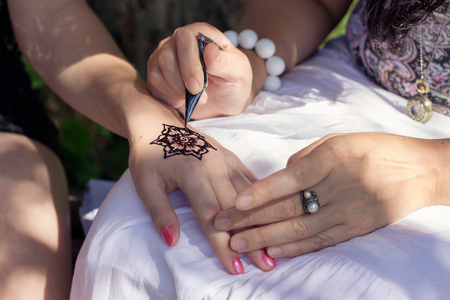 Master mehndi draws henna on a female hand. Selective focus.の写真素材
