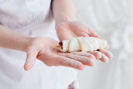 Young beautiful woman preparing homemade croissants. Housewife turns the dough into a croissant. The concept of home cooking. Toning.の写真素材