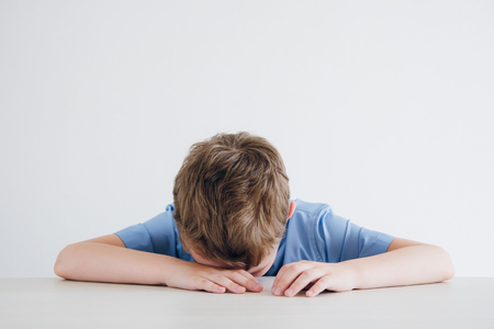 Schoolboy in school uniform covers his face from exhaustion. Toning.の写真素材