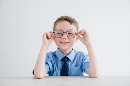 Schoolboy in school uniform and glasses sitting at the Desk. Toning.の写真素材