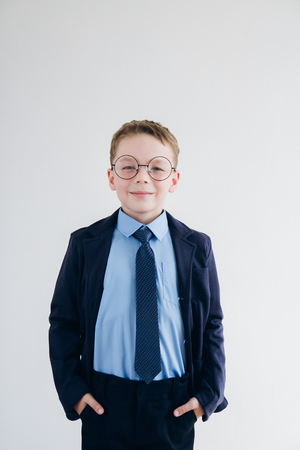 Schoolboy in school uniform and glasses stands on a background of white . Toning.の写真素材