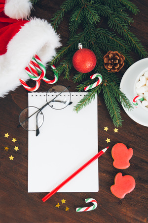 Christmas composition. Table with Santa hat, candy, points, list, Cup of cocoa with marshmallows. Christmas background. The view from the top.の写真素材