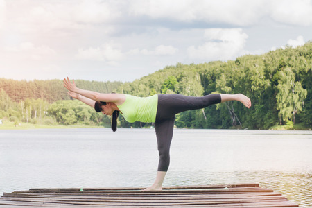 Woman does yoga on the bridge in the summer. Toning.の写真素材