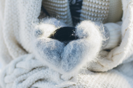 Young beautiful girl in hat and mittens, drinking hot tea from a thermos in the winter. Christmas concept. Toning.の写真素材