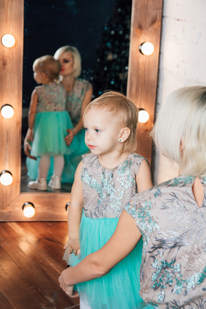 Beautiful young mother and little daughter in puffy skirts made of tulle posing in the new year interior. Christmas concept. Toning.の写真素材