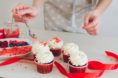Young girl prepares cupcakes. Decorating cupcakes for Valentine's day. The concept of home cooking. Selective focus. Toning.の写真素材