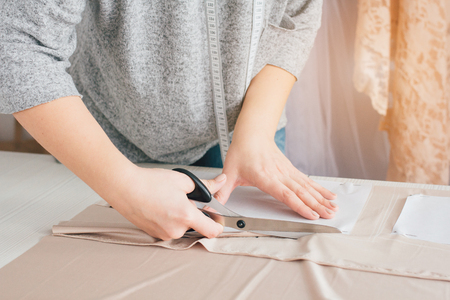 Young seamstress makes clothes cutting fabric. Selective focus. Toning.の写真素材