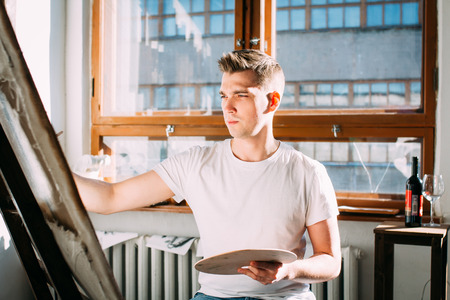 Young man  artist paints a picture in the Studio. Toning.の写真素材