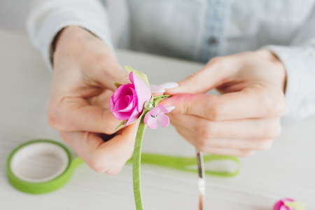 Young woman florist does with his hands a wreath with artificial flowers from Foamiran. Handmade. Master class. The concept of women's Hobbies and business. Selective focus.の写真素材