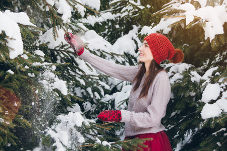 Young beautiful brunette woman having fun in winter forest with fir trees. Toning. The concept of winter respiration.の写真素材