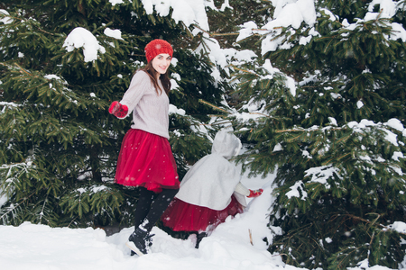 Young beautiful woman and her little daughter have fun in the winter forest with fir trees. Toning. Concept of a family holiday.の写真素材