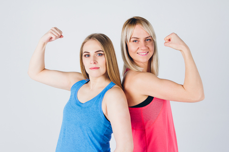Young pregnant girl and her friend in sportswear are engaged in fitness. The concept of a healthy lifestyle. Toning.の写真素材