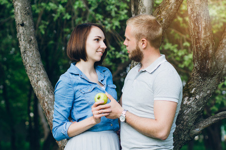 Young couple in love have a rest in the summer Apple orchard. The concept of a family holiday. Toning.の写真素材