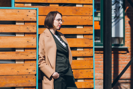 Young beautiful woman in a business suit and coat posing on the streets. Toning.の写真素材