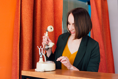 Young beautiful woman calling on a retro phone. Toning.の写真素材