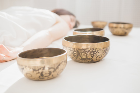 Young beautiful girl doing massage therapy singing bowls in the Spa. The concept of relaxation and alternative medicine. Toning.の写真素材