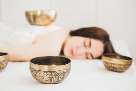 Young beautiful girl doing massage therapy singing bowls in the Spa. The concept of relaxation and alternative medicine. Toning.の写真素材
