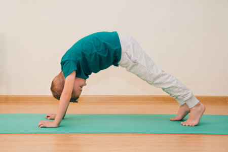 Cute little boy is learning to do yoga in the gym. The concept of sport and healthy lifestyle.