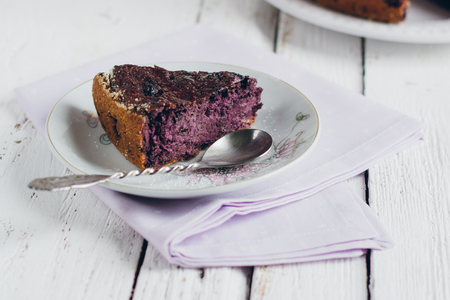 Homemade blueberry pie on a white wooden table next to a vase of lilacs. Gentle toning. Selective focus.の写真素材