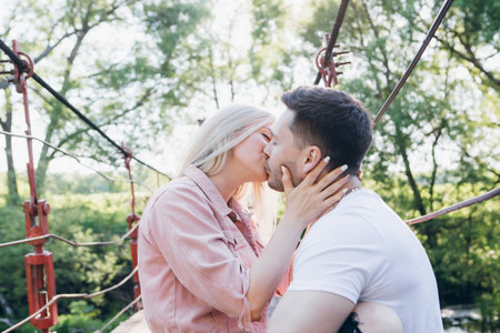 Young couple guy and girl on the bridge over the river and kiss in summer at sunset. The concept of...