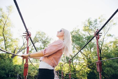 Young beautiful blonde woman standing on the bridge in the setting sun. Toning.の写真素材