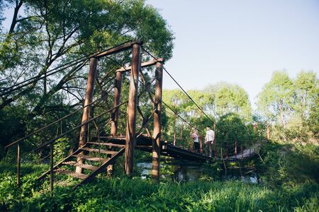 Young couple guy and girl on the bridge over the river and kiss in summer at sunset. The concept of freedom, love and family. Toning.の写真素材