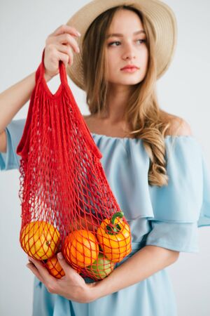 Young beautiful girl with fresh fruit in a string bag. The concept of zero waste. Toning.の写真素材