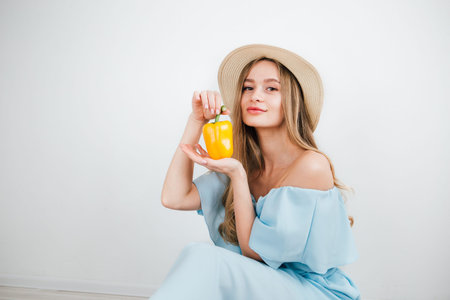 Young beautiful girl holding fresh yellow pepper on white background. The concept of healthy eating. Toning.の写真素材