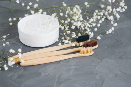 Natural bamboo toothbrushes and tooth powder on a grey background. Concept of an eco-friendly...
