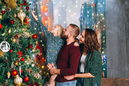 Nice family is decorating a Christmas tree. Happy new year concept. Toning.の写真素材