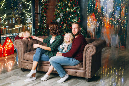 Happy young family with two children at the Christmas tree. Happy new year concept. Toning.の写真素材