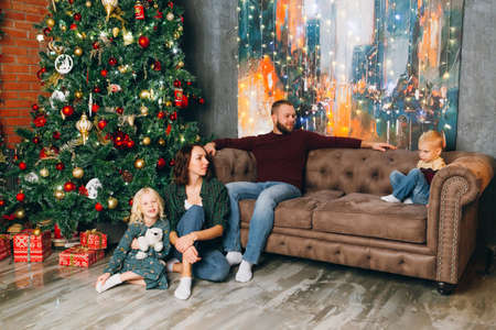Happy young family with two children at the Christmas tree. Happy new year concept. Toning.の写真素材