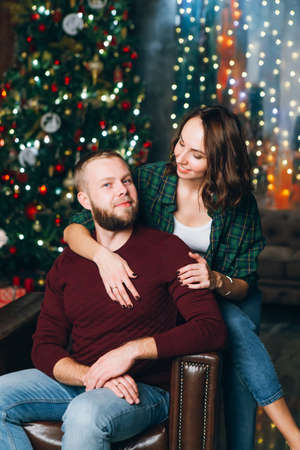 Cute young family husband and wife at the Christmas tree. Happy new year concept. Toning.の写真素材