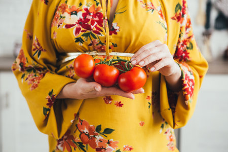 Young cute pregnant girl preparing vegetable salad in the kitchen. The concept of healthy eating. Toning.の写真素材