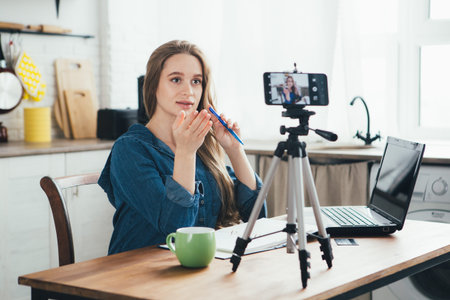 Young pretty pregnant girl works at home in self-isolation mode in quarantine and records videos on...