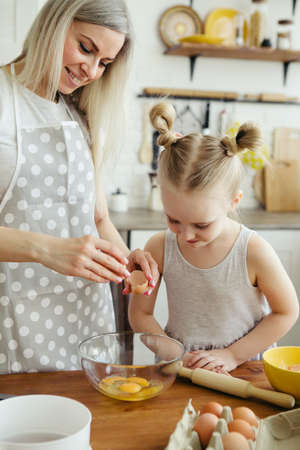 Cute little girl helps mom bake cookies in the kitchen. Happy family. Toning.の写真素材