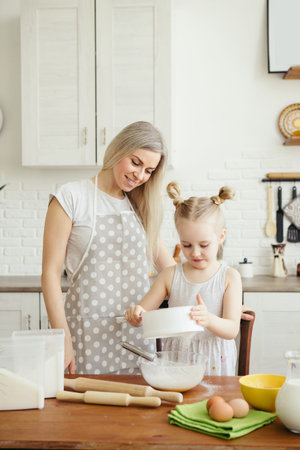 Cute little girl helps mom bake cookies in the kitchen. Happy family. Toning.