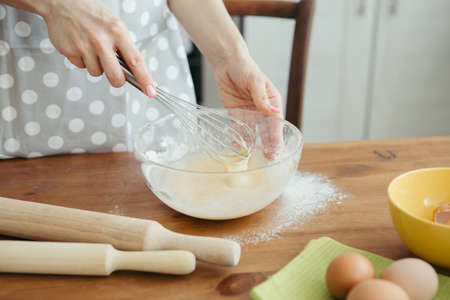 Young beautiful woman kneads dough for baking cookies in the kitchen. Toning.の写真素材