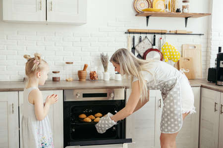 Cute little girl helps mom bake cookies in the kitchen. Happy family. Toning.の写真素材