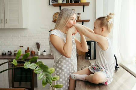 Young beautiful woman hugs and kisses her cute little daughter. Toning.の写真素材