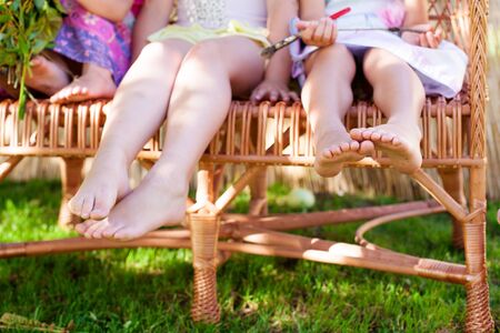 Childrens bare feet. Children sit in a wicker chairの写真素材