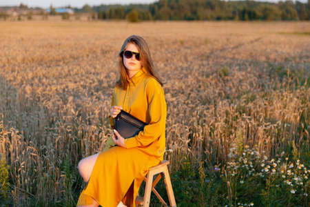 A young woman poses in a yellow fashionable silk dress.の写真素材